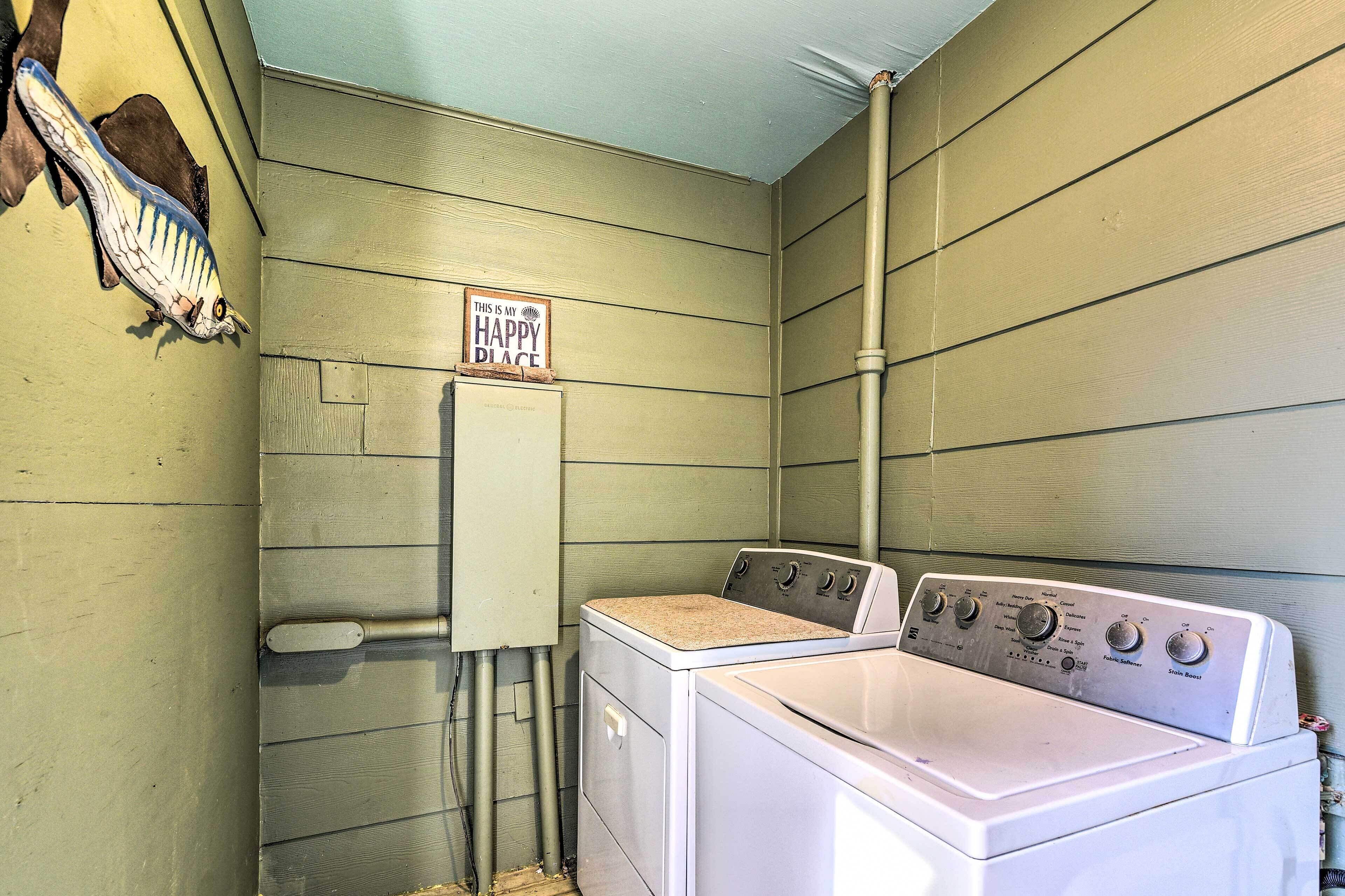 A laundry room with a washing machine and a dryer, a utility meter, and a sign that says 'THIS IS MY HAPPY PLACE.'