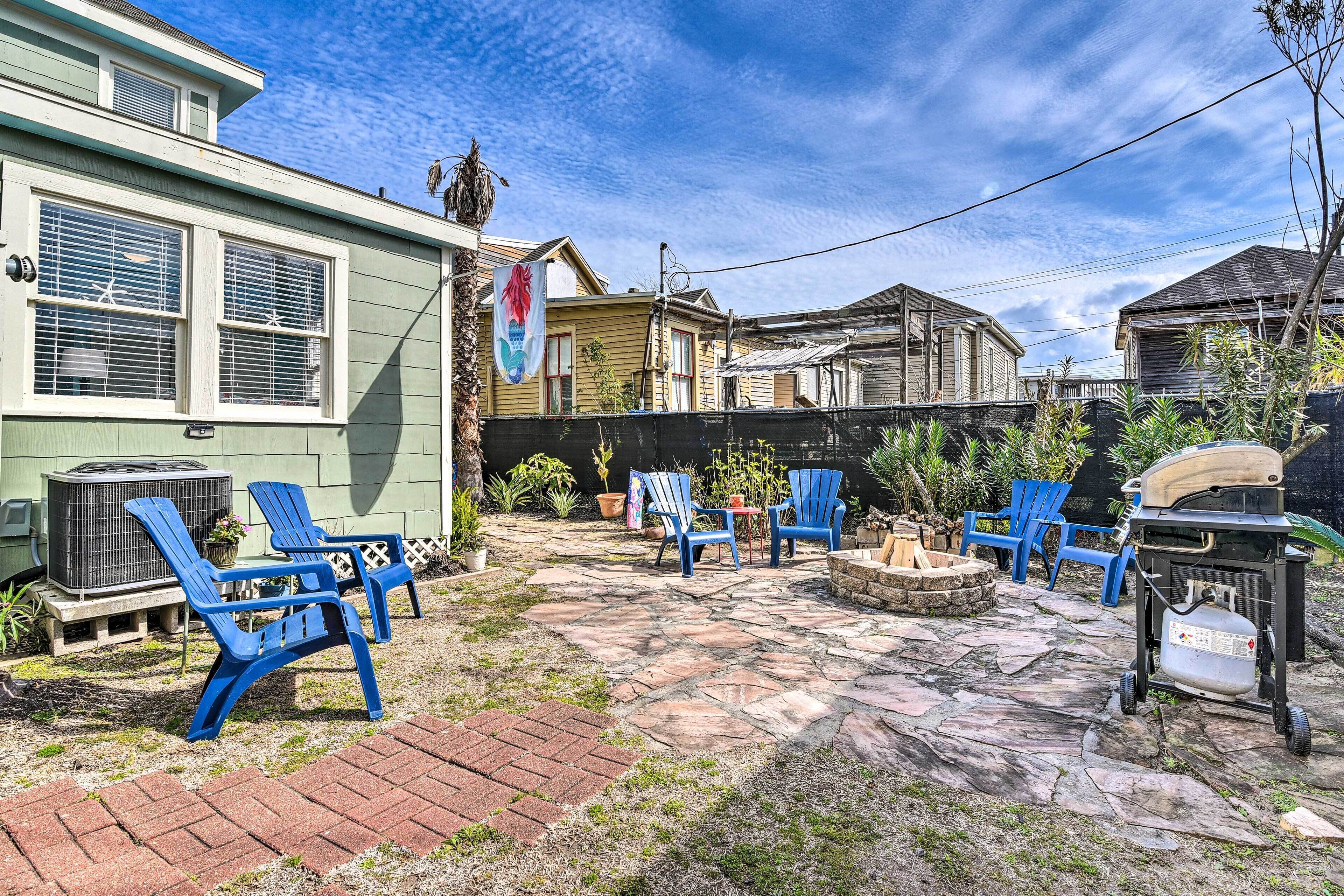 Un jardin avec une terrasse en pierre, un espace salon extérieur et un barbecue.