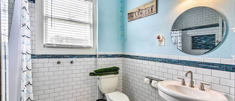 A bathroom with a toilet, sink, and a window with blinds.