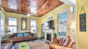 A cozy living room with a fireplace, leather sofas, a green coffee table, and a wooden ceiling. - Historic Galveston Hideaway, Walk to the Beach! (Galveston)