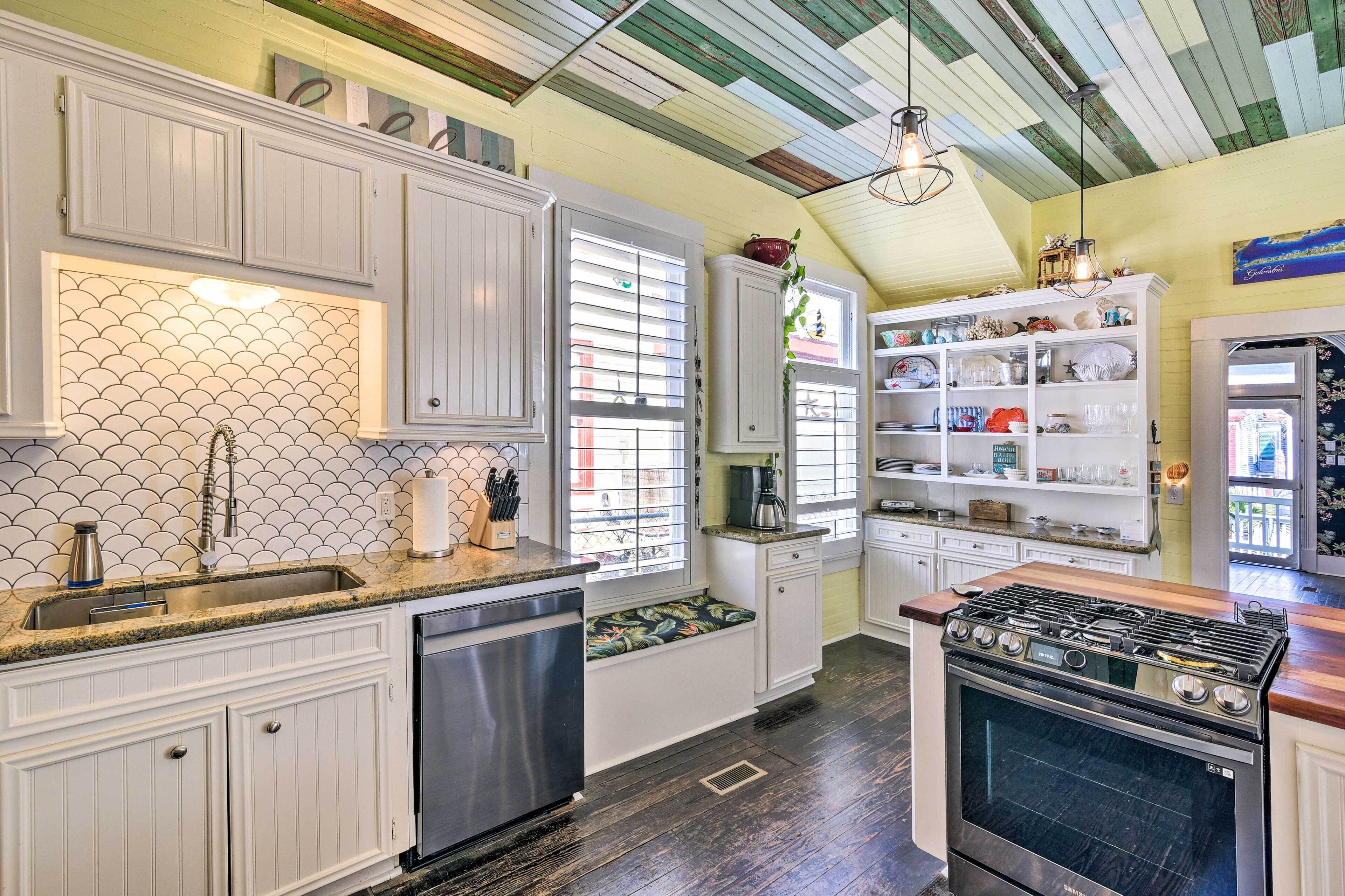 Una cocina con armarios blancos, estufa de acero inoxidable y una ventana con persianas.