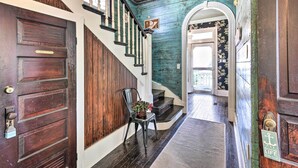 A wooden staircase with a dark finish, a chair with a plant, and a door with a brass doorknob. - Historic Galveston Hideaway, Walk to the Beach! (Galveston)