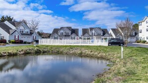 A row of single-family homes with a small pond in the foreground.