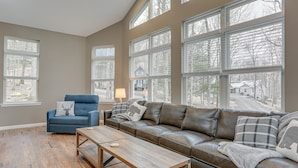 A spacious living room with a large brown leather sofa, a blue armchair, and a wooden coffee table. - Hike, Swim & Ski: Home w/ Deck in Lackawaxen (Lackawaxen)
