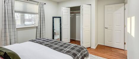 A bedroom with a bed, a closet, and a window with curtains.