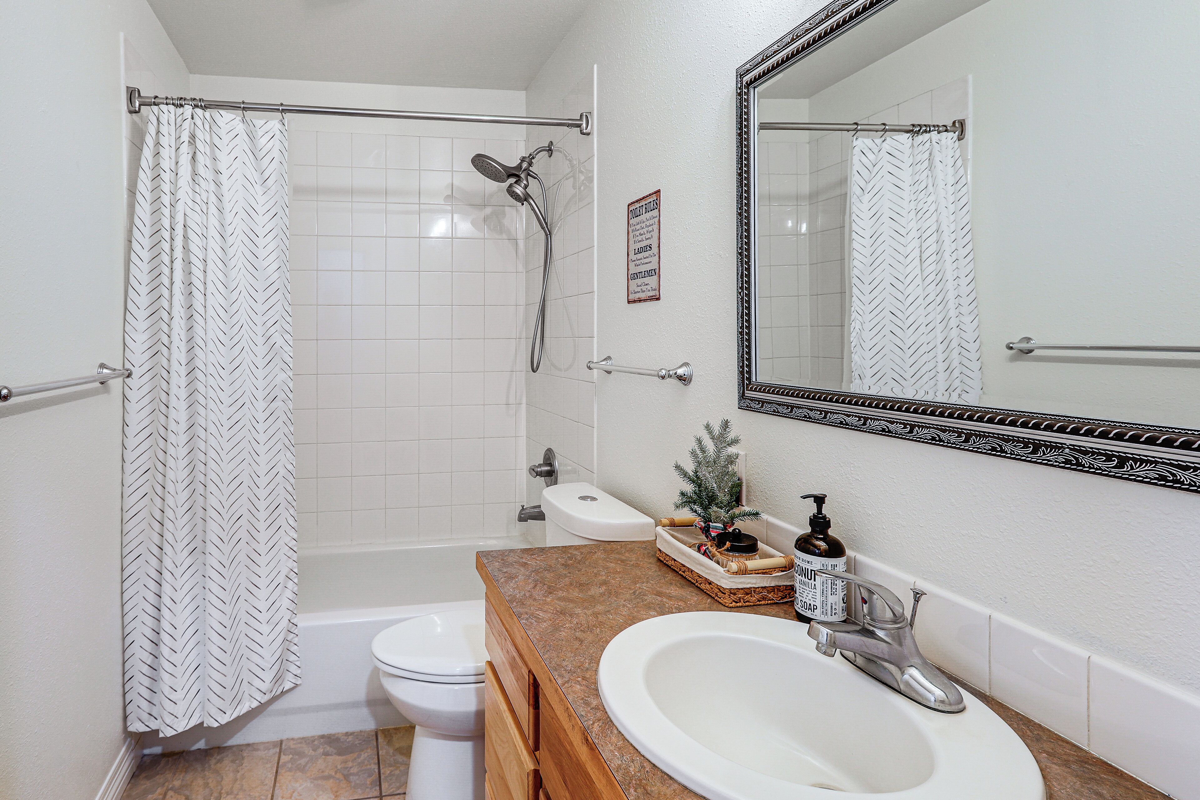 Ein Badezimmer mit Dusche, Toilette, Waschbecken und Spiegel.