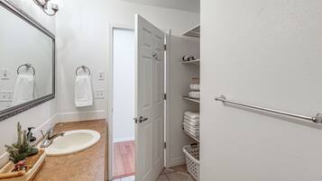 Un baño con lavamanos, espejo y toallero.