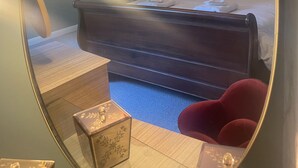 Une chambre à coucher avec un lit, une table de chevet, un miroir et une chaise rouge.