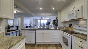A modern kitchen with white cabinetry, granite countertops, a built-in dishwasher, and a microwave. - 1501 Island Club - Folly Field - 2 Bed 2 Bath Sleeps 4 - Hilton Head Rentals (Hilton Head island)