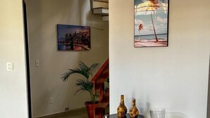 Un hall d’entrée spacieux avec un escalier moderne, une petite table agrémentée d’objets décoratifs et une plante en pot.