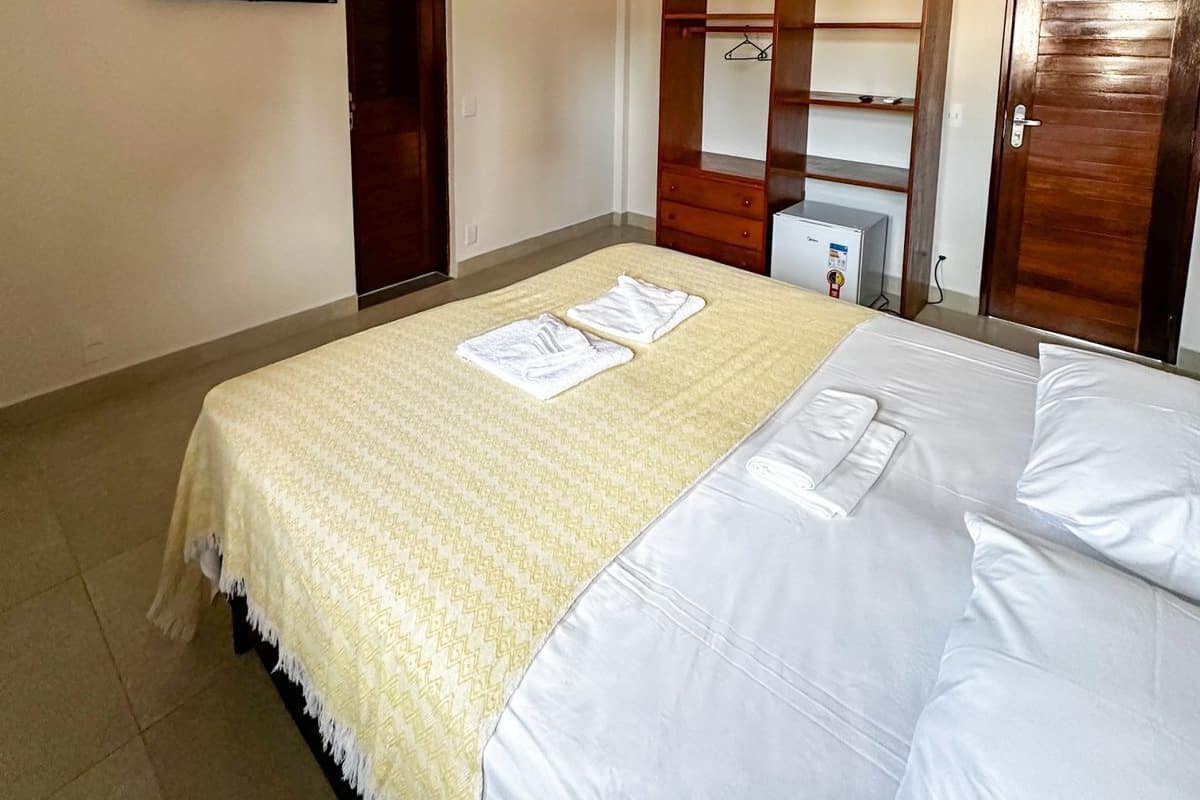 Una habitación de hotel con cama, armario, televisor y escritorio con computadora.