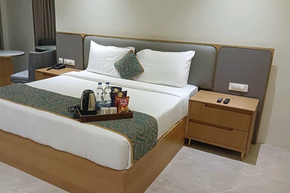 Une chambre d’hôtel avec un grand lit, des tables de chevet, une petite table ronde et une chaise.