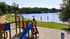 A playground with a slide and climbing structures near a lake. - La Chalaumière (Chalaux)