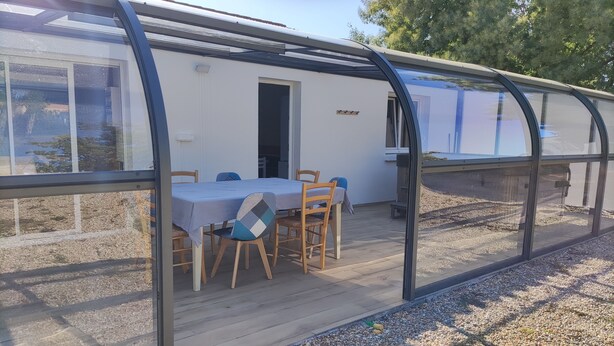 A covered patio area with a table and chairs, a door, and a window.