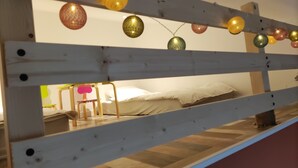 A bunk bed with a wooden frame and a mattress. There are colorful spherical lights hanging above the bed.