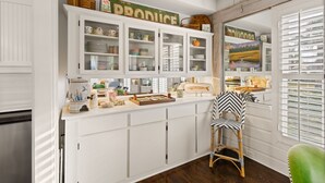 Una cocina con armarios blancos, una isla de cocina y una ventana con persianas.