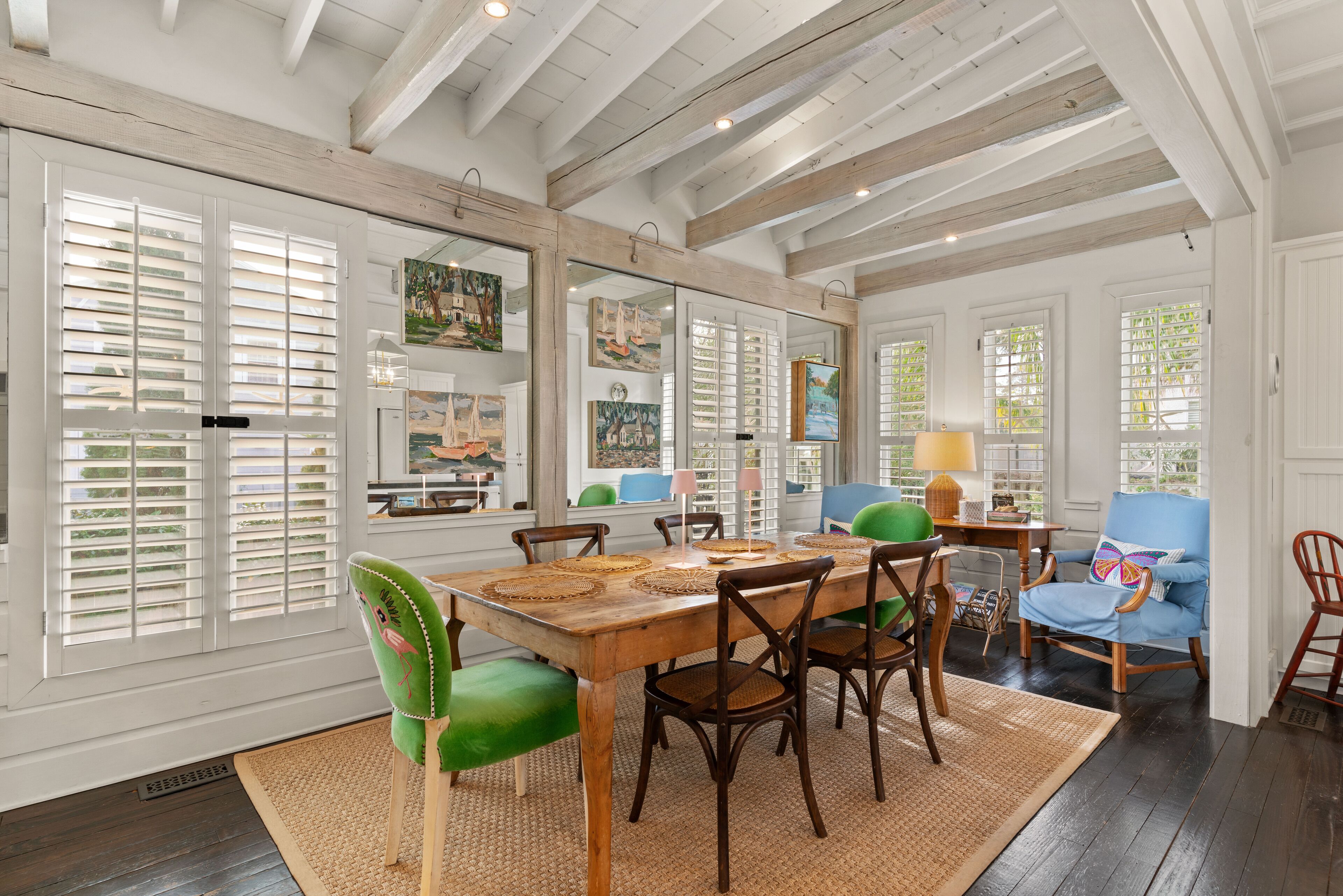A dining area with a wooden table, chairs, and a large window with blinds.