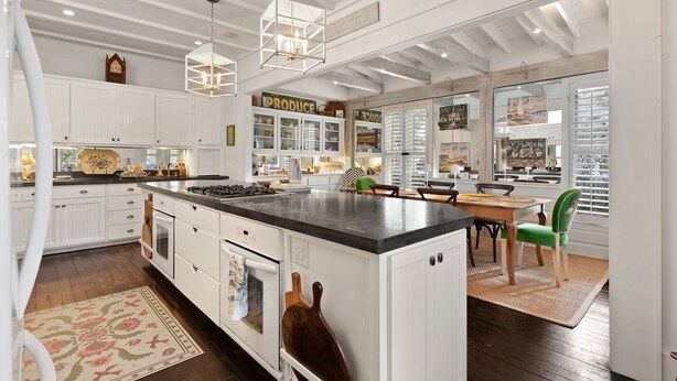 Una cocina amplia con armarios blancos, una isla grande y un comedor con una silla verde.