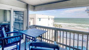 A balcony with a view of the ocean, a table, and chairs. - Almost Heaven - Beautiful Oceanfront Condo with a Pool! (Murrells Inlet)