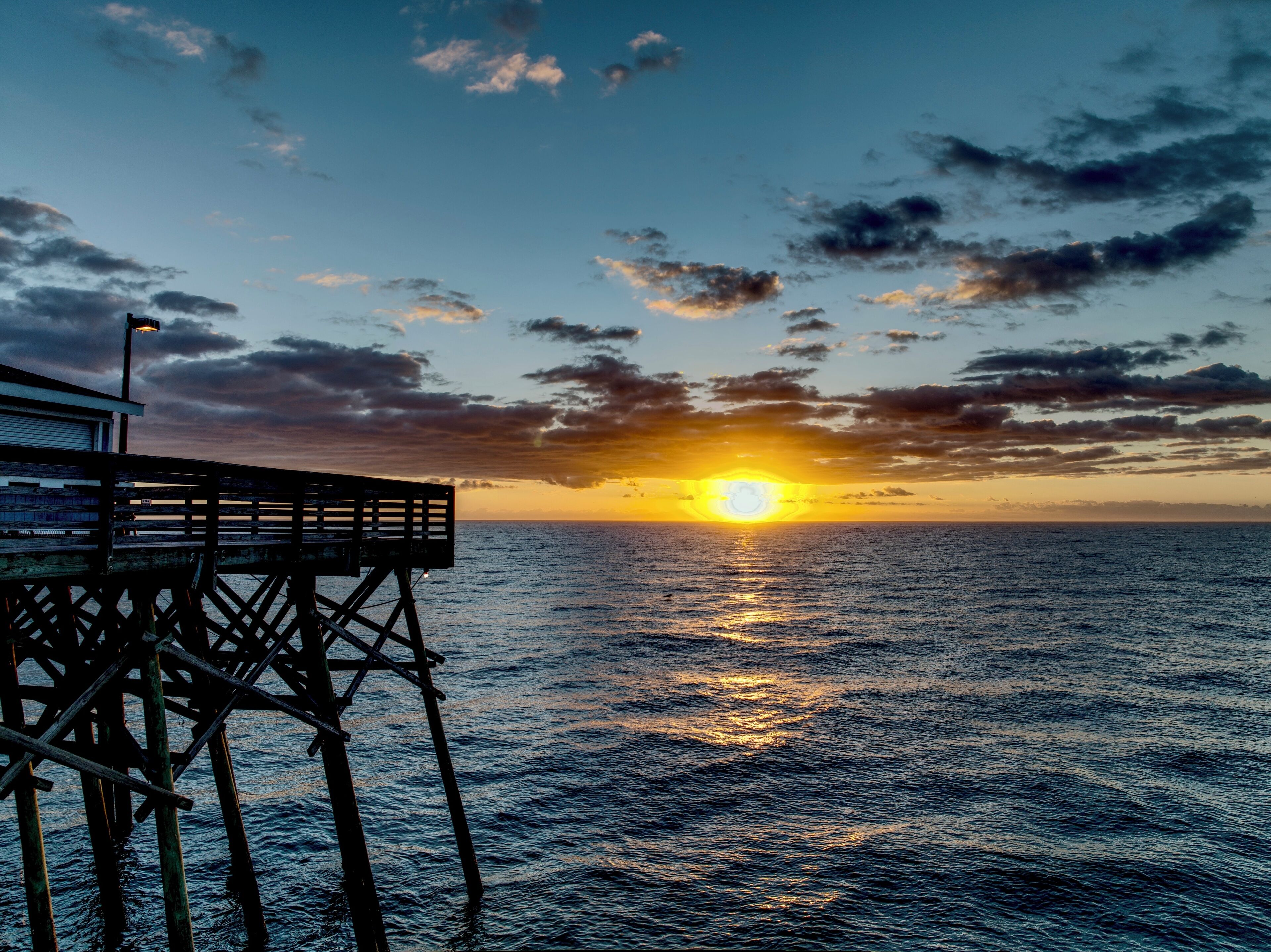 A pier extending into the water with a sunset in the background.