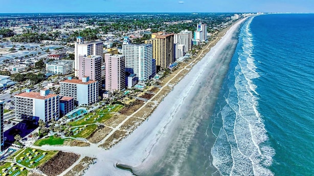 A coastal cityscape with high-rise buildings along a beach, a clear sky, and a calm sea. - Almost Heaven - Beautiful Oceanfront Condo with a Pool! (Murrells Inlet)
