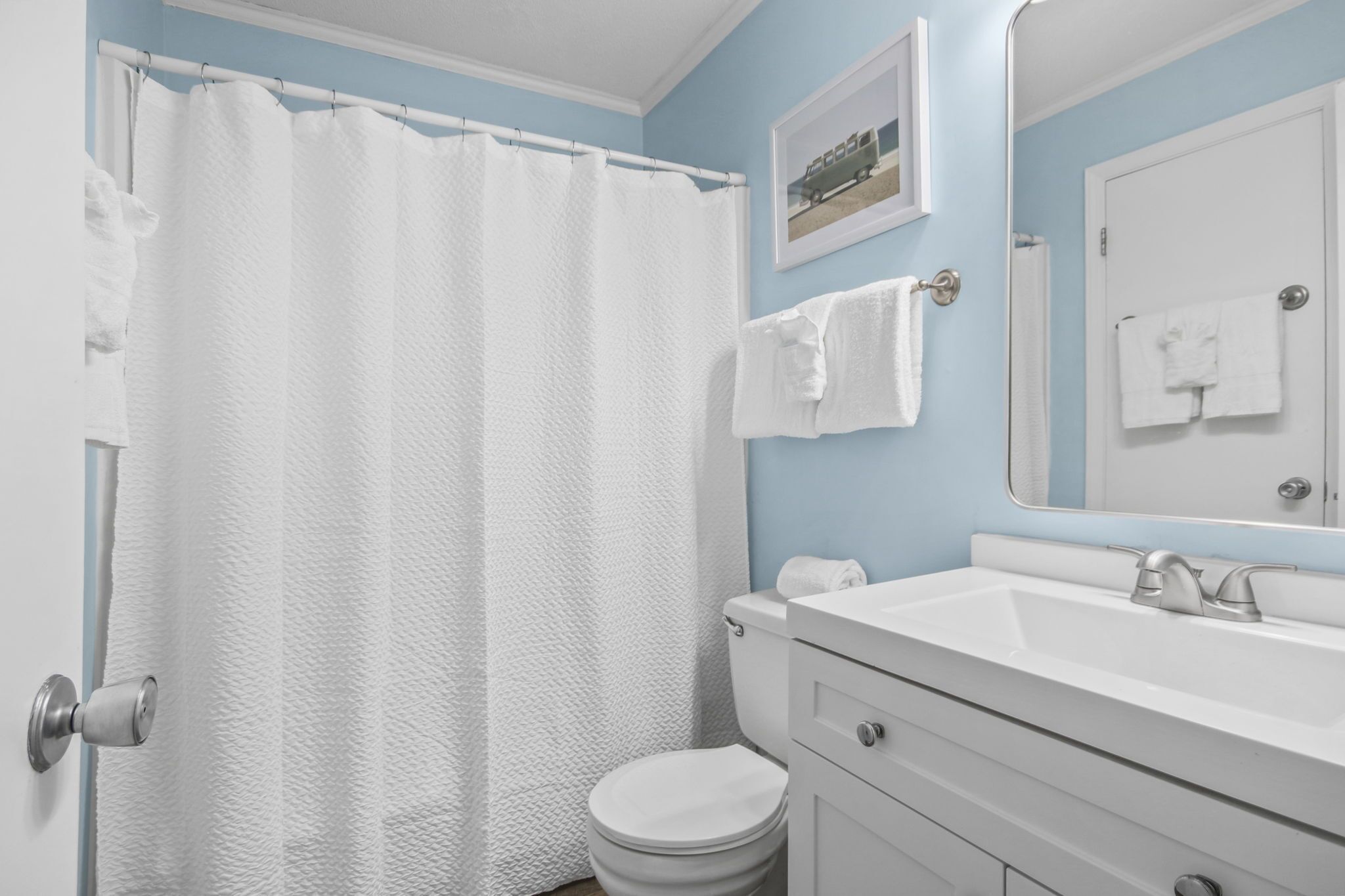 Un baño con inodoro y lavamanos blancos, y una cortina de ducha.