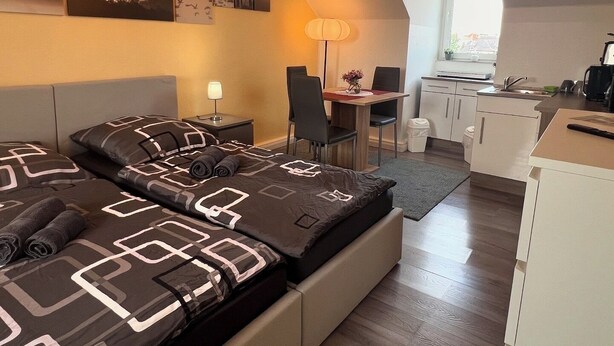 Ein modernes Hotelzimmer mit Bett, Schreibtisch und einer Küchenzeile.