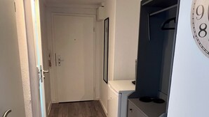 Ein Flur mit einer weißen Tür, einem kleinen weißen Schrank und einem blauen Tresen mit einer Uhr.