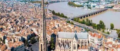 Una cattedrale con un campanile slanciato, circondata da un’area urbana densamente popolata con diversi edifici e un fiume sullo sfondo.