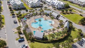 A resort with a central swimming pool, multiple guest villas, and a parking area. - Prominence Townhome with LSV and Bikes (Watersound)