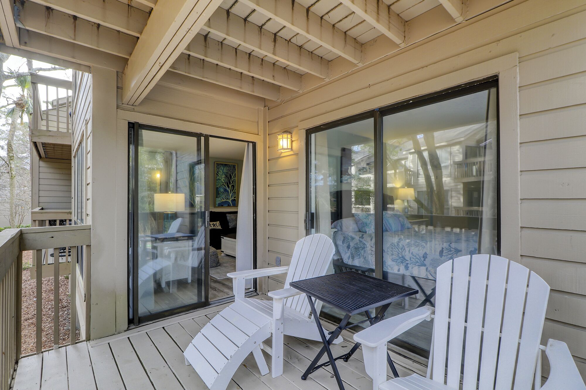 A covered outdoor seating area with a table and chairs, a sliding glass door, and a view of the backyard.