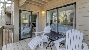 A covered outdoor seating area with a table and chairs, a sliding glass door, and a view of the backyard.