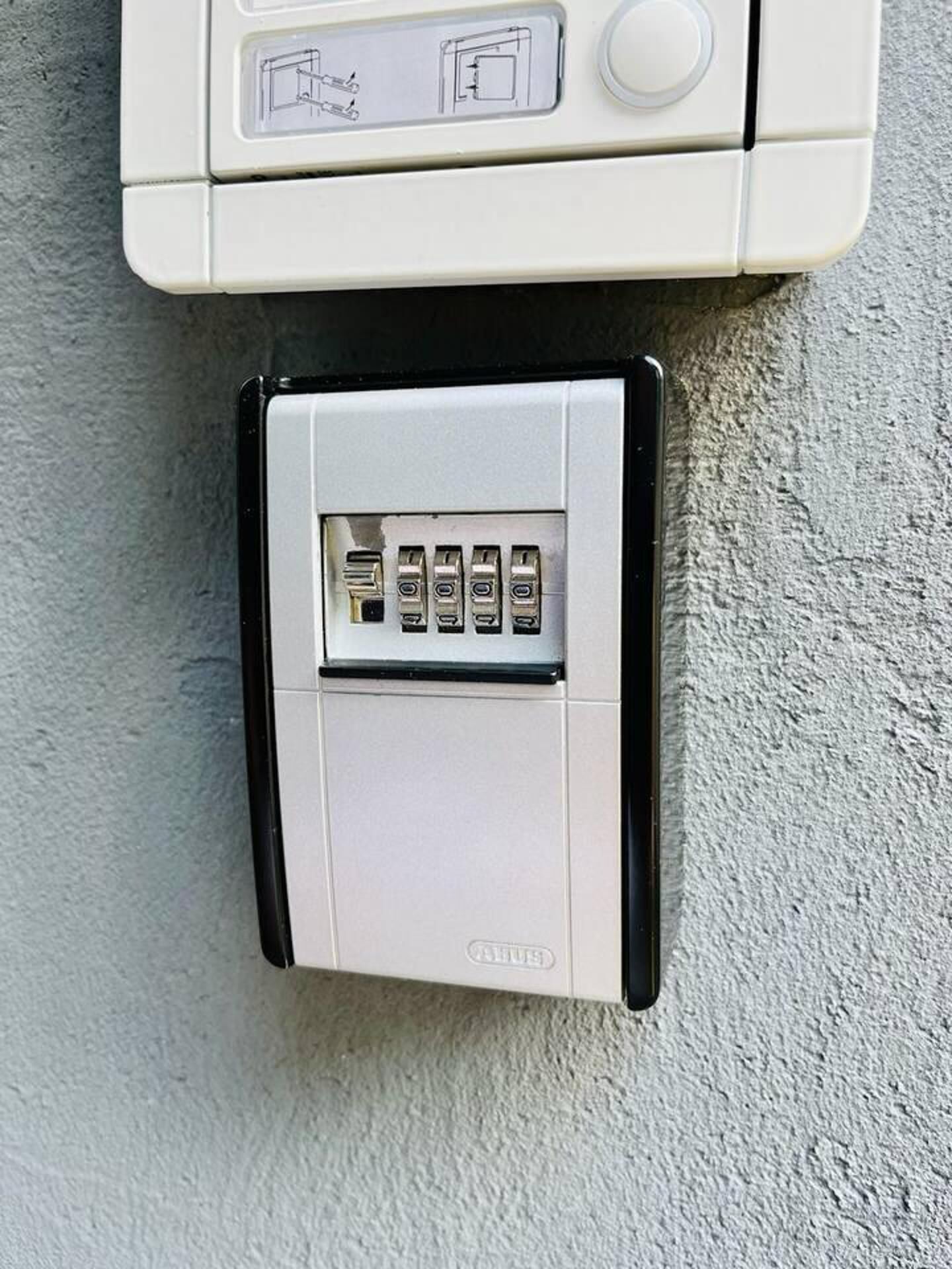 Et intercomsystem fastgjort på væggen, med et tastatur og en døråsning.