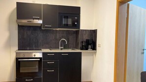 Uma cozinha compacta com forno embutido, micro-ondas e máquina de café.