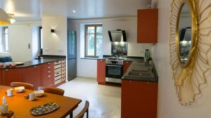 Une cuisine moderne dotée d’un îlot central, d’un coin repas avec une table et des chaises, et d’un grand miroir décoratif accroché au mur.