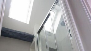 Une salle de bain dotée d’une douche à paroi de verre, d’un miroir et d’un lavabo avec un plan de travail en marbre.