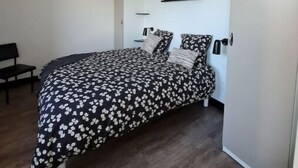 Une chambre à coucher comprenant un lit, un banc, un luminaire suspendu et une étagère intégrée.