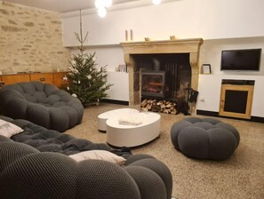 A cozy living room with a fireplace, a Christmas tree, and modern furniture.