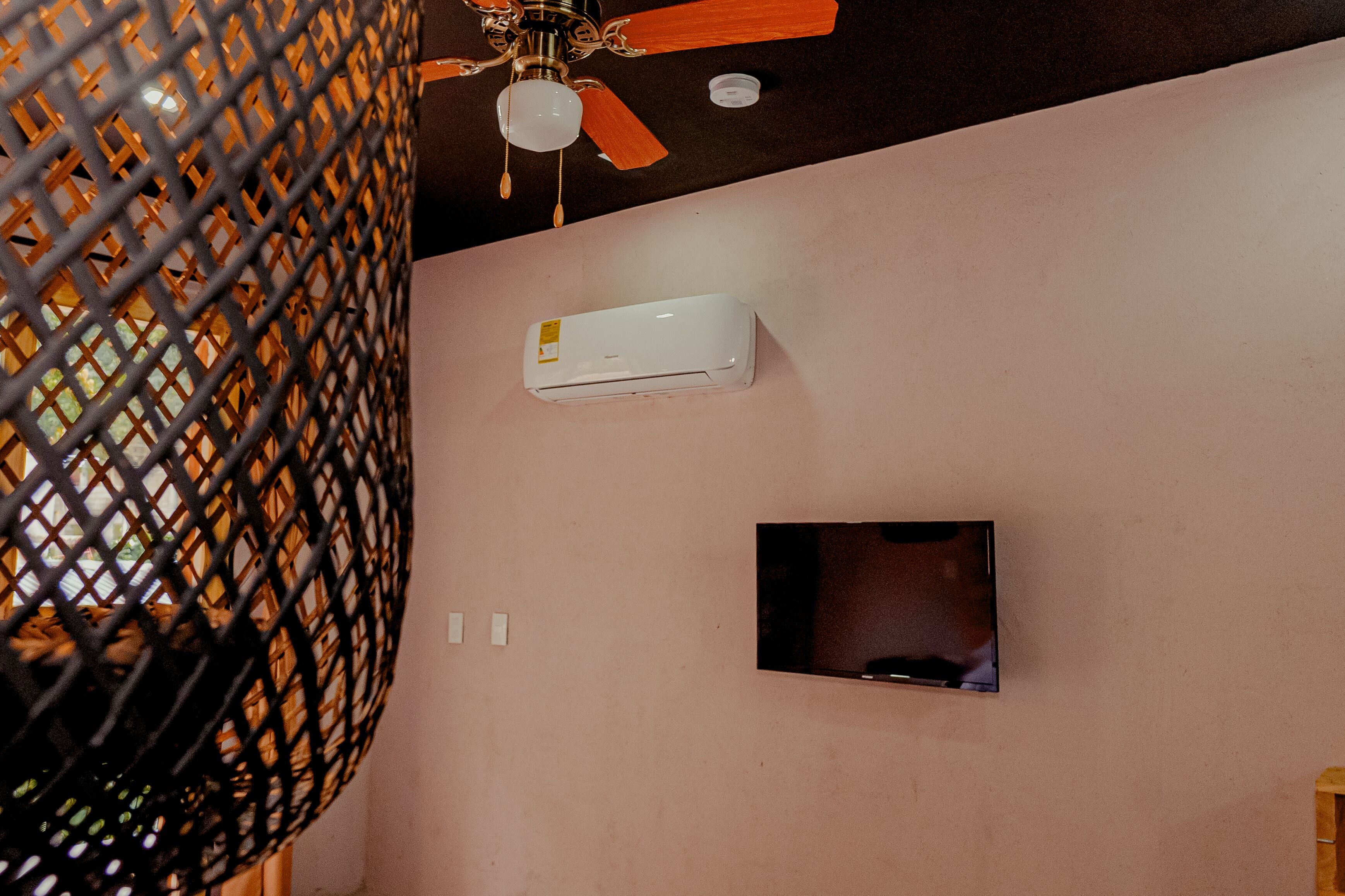 A room with a ceiling fan, an air conditioning unit, and a mounted television.