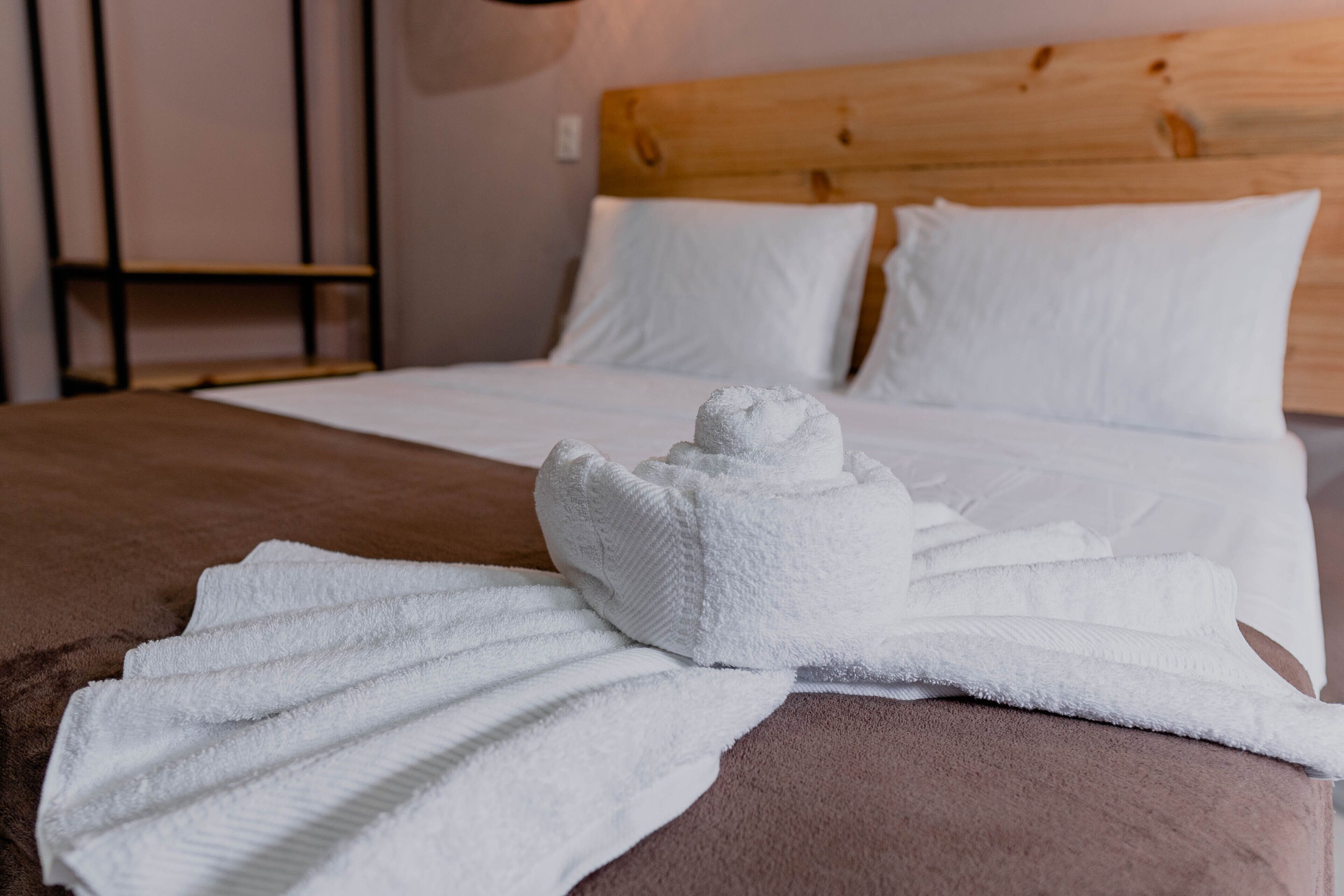 A neatly made bed with white linens and a folded towel on the bed.