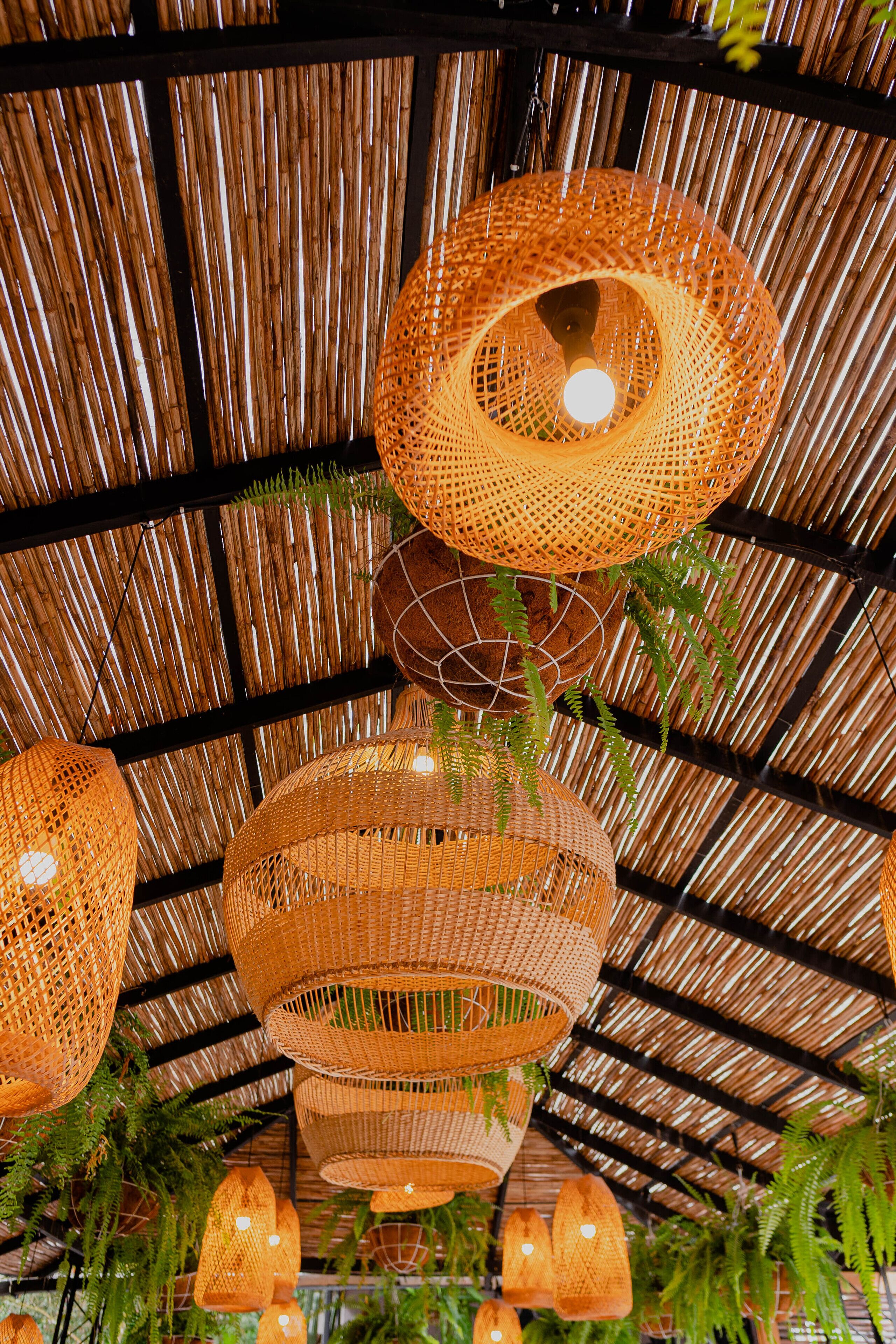 A ceiling with woven rattan lampshades and hanging pendant lights.
