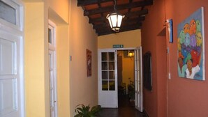 A hallway with a white door, a potted plant, a painting, and a sign indicating the exit.