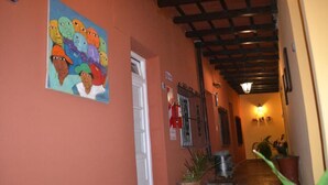 A narrow hallway with a wooden ceiling, a door on the left, and a wall-mounted light fixture on the right.