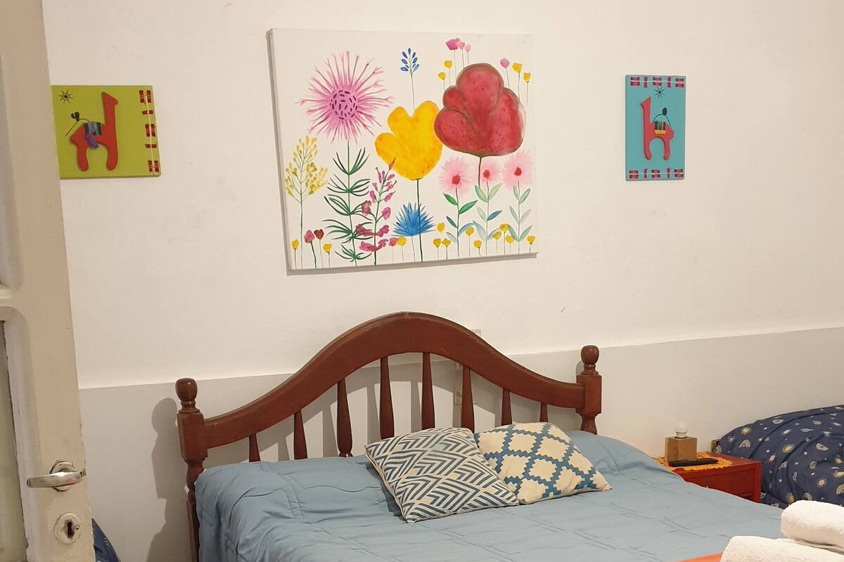 A bedroom with a wooden bed, blue and orange bedding, and two side tables.