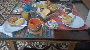A breakfast table with croissants, orange juice, and coffee cups.