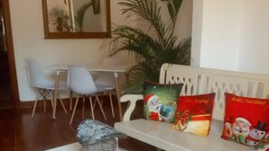 En stue med en hvid sofa, et hvidt sofabord med skuffer, en grå vase og en hvid måtte.