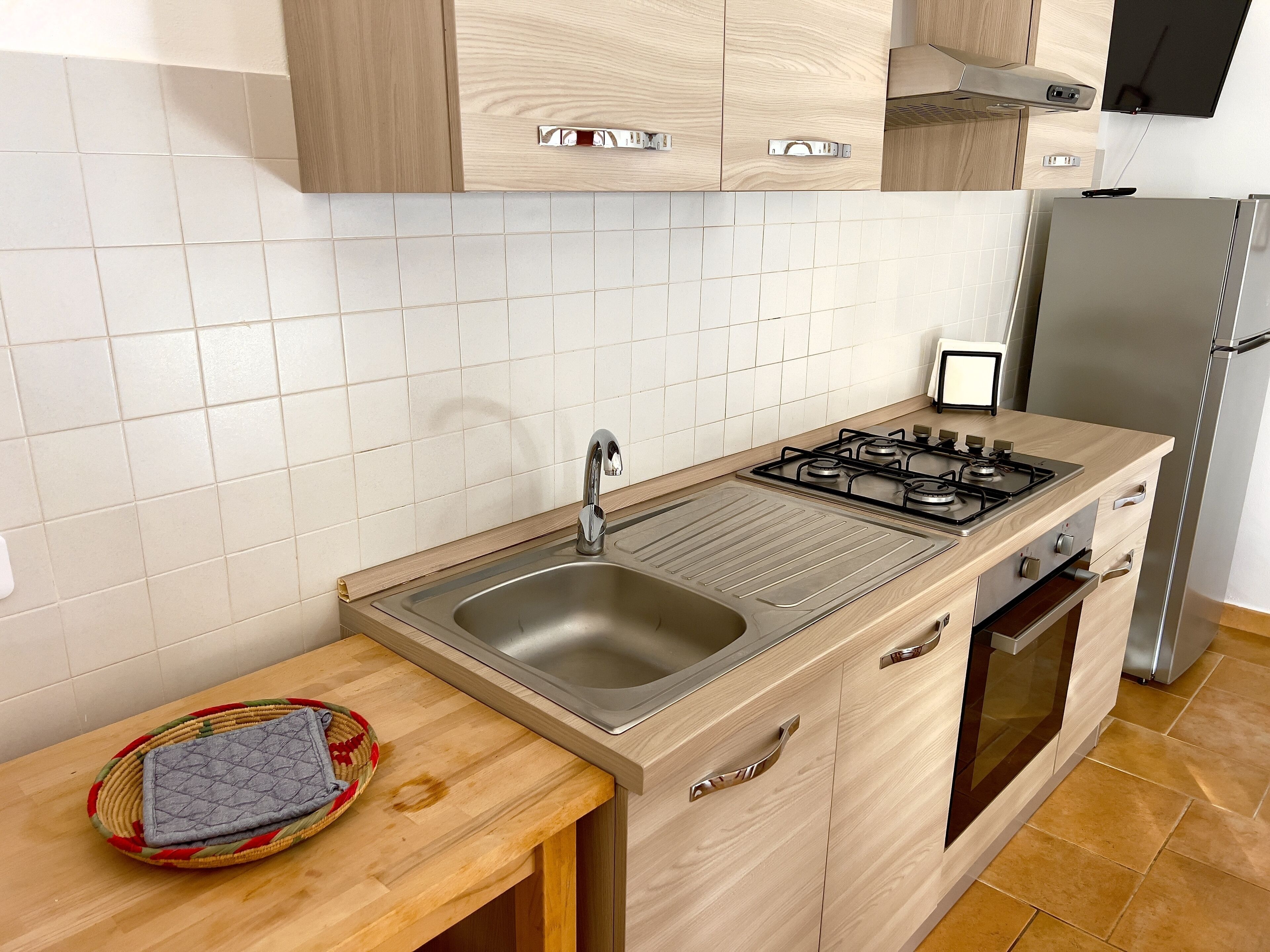 A modern kitchen with a stainless steel sink, a gas stove, wooden cabinets, and a built-in oven.