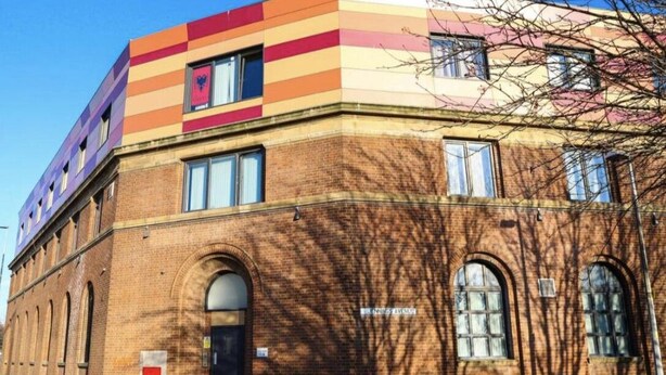 Un edificio de varios pisos con fachada de ladrillo y una sección superior colorida.