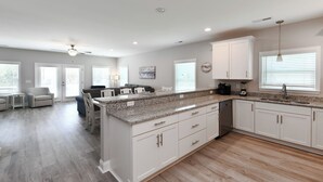 A spacious kitchen with granite countertops, white cabinetry, and a large island.