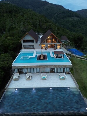A two-story house with a large swimming pool and outdoor seating.